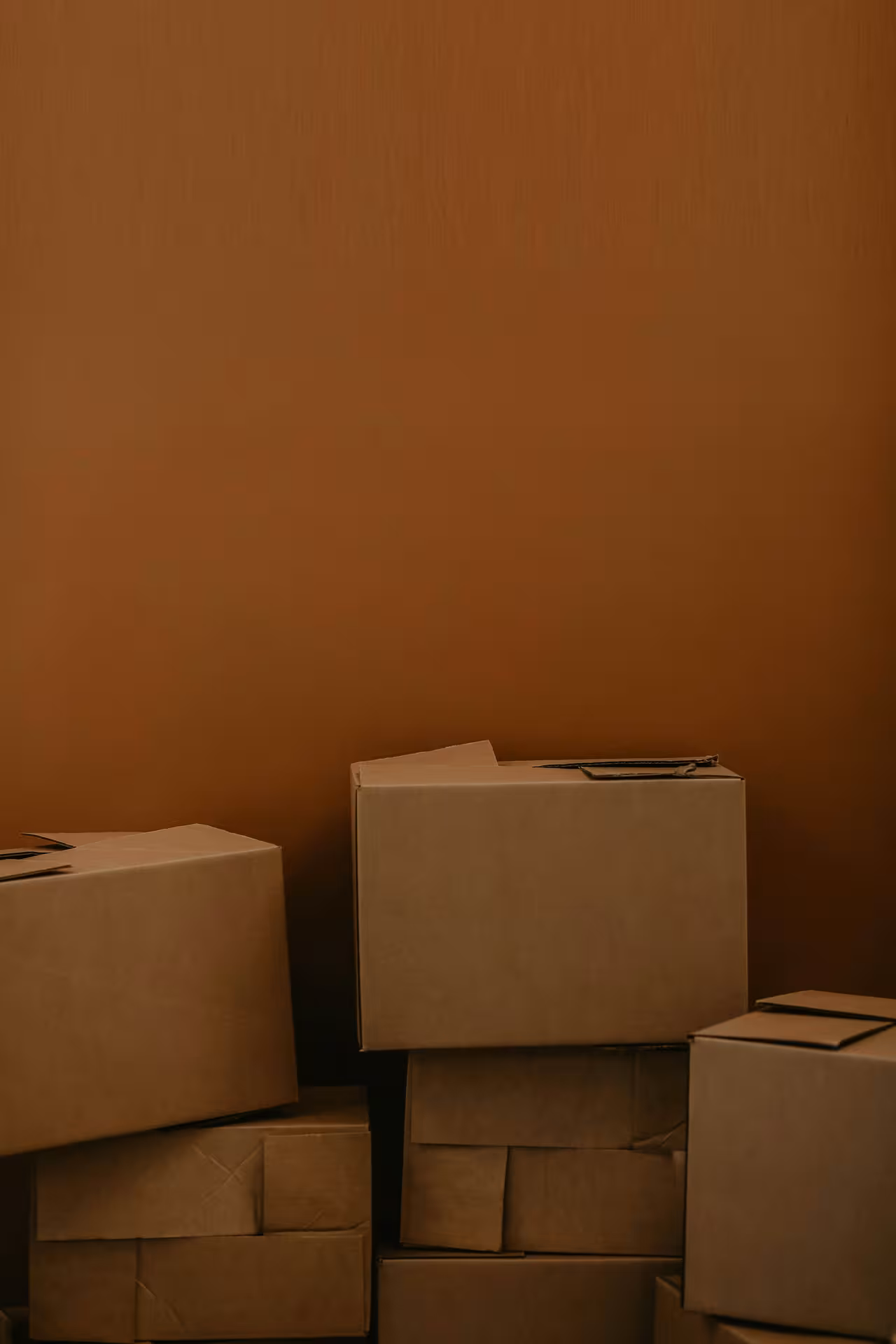 Stacked cardboard moving boxes piled against a wall.